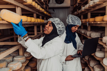 Business of a Muslim partners in a cheese warehouse, checking the quality of cheese and entering data into laptop