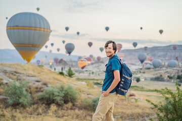 Tourist man looking at hot air balloons in Cappadocia, Turkey. Happy Travel in Turkey concept. Man on a mountain top enjoying wonderful view