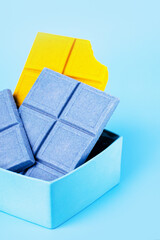Lemon ginger yellow chocolate and blue chocolate with spirulina on a blue background, copy space
