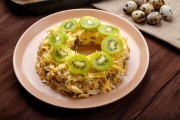Layered salad with chicken and kiwi next to quail eggs on the table.