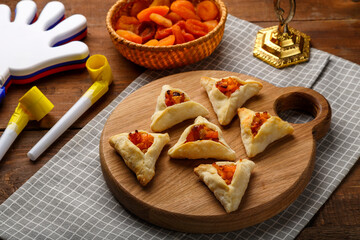 cookies triangles gometashi mishloach manot for Purim laid out on a wooden board on a napkin next to clappers and a whistle.