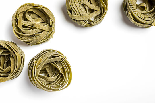 Green spinach tagliatelle pasta nests on white background - Powered by Adobe