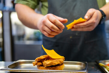 chef hand cooking chickenburger on restaurant kitchen