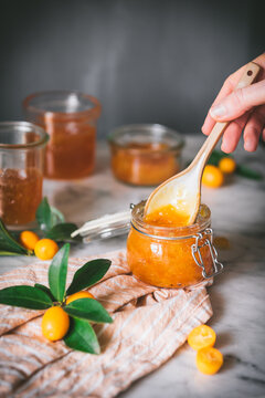 Crop person taking kumquat jam with spoon