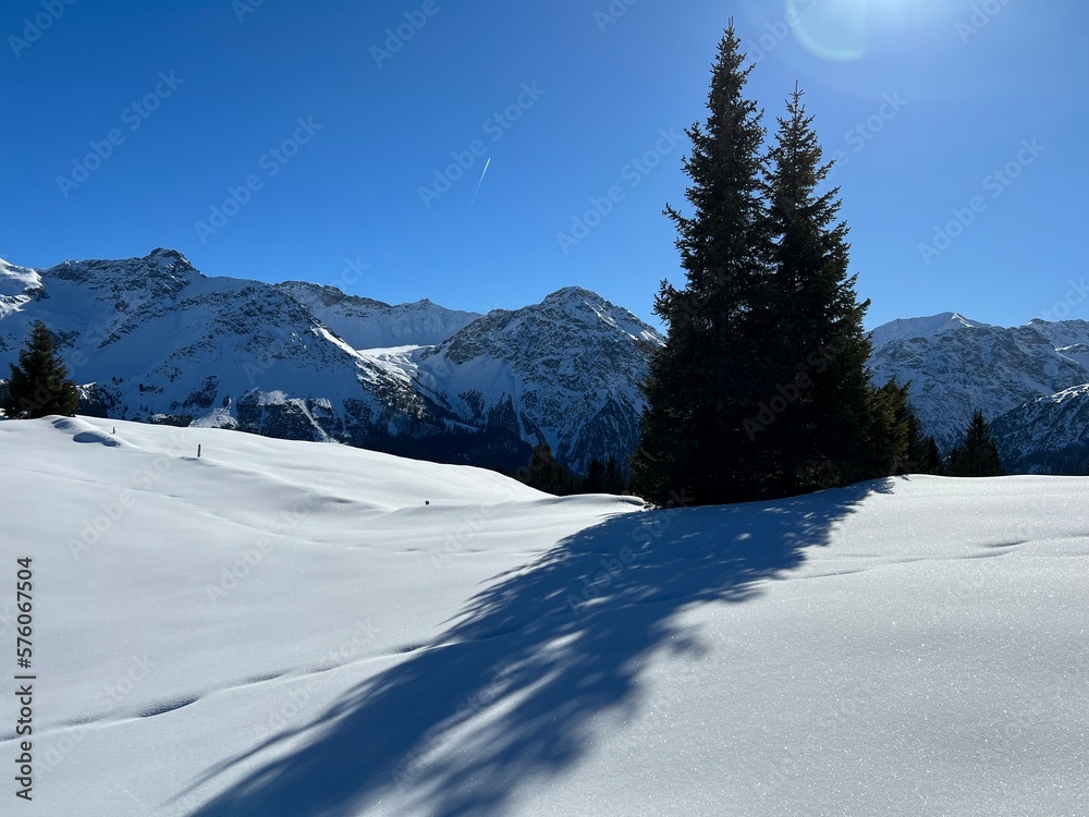 Wall mural a magical play of sunlight and shadow during the alpine winter on the snowy slopes above the mountin