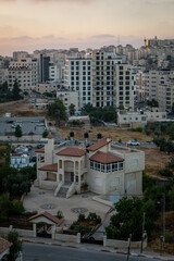 Obraz premium Ramallah Cityscape at Dawn with Sunset, High Buildings and Trees Facing the Sun