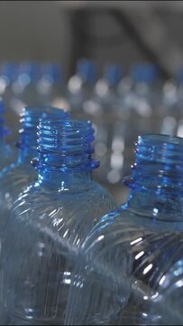 Vertical video. Empty blue plastic bottles are moved on a conveyor belt. Mineral water production plant.