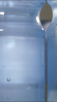 Vertical video. Close up of a plastic bottle filled with carbonated mineral water. Floating bubbles. Conveyor line of the food industry.