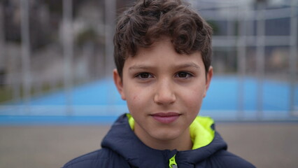 Portrait of a happy handsome young boy standing outside. Closeup face of a smiling preteen male kid looking at camera