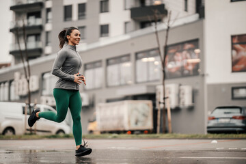 Fototapeta na wymiar A happy healthy sportswoman is running on the street downtown.
