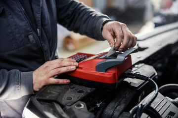 Close up of a mechanics using device for car battery checkup.