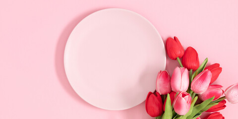 Flowers composition romantic. Flowers pink tulips and pink empty plate on pastel pink background....