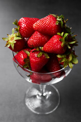 A glass beaker with bunch of fresh strawberries on dark background