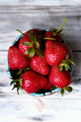 Fresh strawberries in bowl on white wooden table. Top view