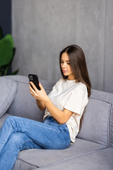 Obraz premium Portrait beautiful young woman use smart mobile phone on sofa in living room interior