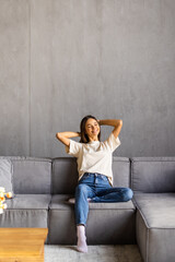 Portrait of a woman relaxing on a sofa after work at home sitting on a sofa in the living room at...