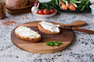 Appetizing toasted sandwiches with cream cheeses with green hot peppers on a beautiful wooden cutting board.