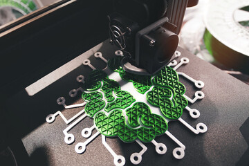 3d printer produces green electrified brain sculpture in striking light. filament rolls in...