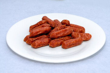 Sausage sausages on a white plate on a light background