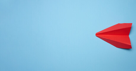 Red paper airplane on a blue background, travel concept, top view