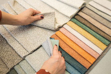 Close-up  of woman choosing fabrics swatches for sofa in store. Interior designer looking materials...