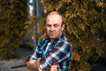 Happy man in the park on the background of plants. Casual clothes, urban style. People around us. Male portrait.