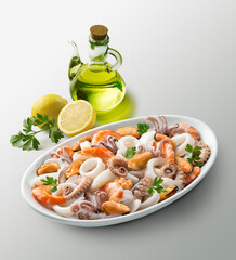 Oval white plate with seafood salad lemons parsley and cruet with oil