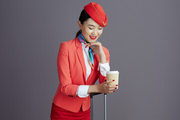 pensive stylish asian female stewardess against gray background
