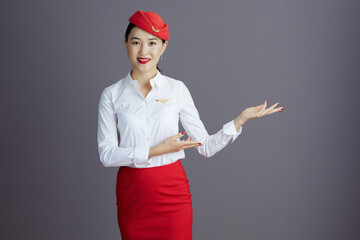 smiling air hostess asian woman welcoming isolated on grey