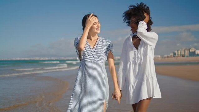 Lgbt couple holding hands walking ocean beach. Happy lesbian couple relationship