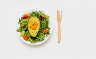 Baked egg with avocado and lettuce leaves on white plate. Fodmap diet concept.