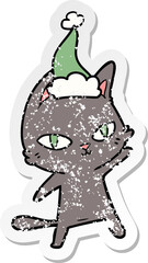 distressed sticker cartoon of a cat staring wearing santa hat