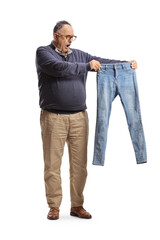 Fototapeta premium Full length portrait of a shocked mature man holding a small pair of jeans