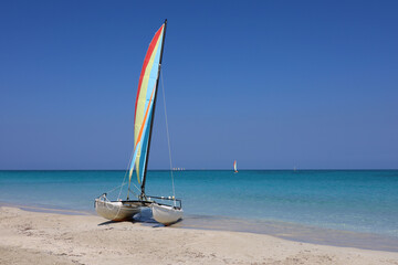 Sailing catamaran on a sand on blue ocean background. Water sports on a beach of Atlantic ocean