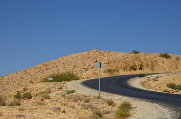 Landscapes of a road crossing the dry desert of Jordan under a bright sunny day
