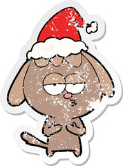 distressed sticker cartoon of a bored dog wearing santa hat
