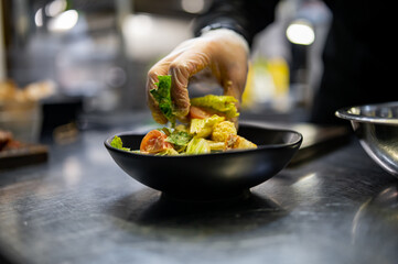 Chef cooking Caesar salad on restaurant kitchen