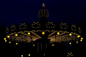 Night carousel illuminated with yellow lights
