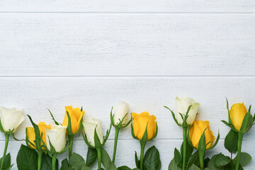 Happy Easter. Yellow and white roses on white wooden background. Easter background with copy space. Floral pattern. Greeting card. Mock up. Space for text.