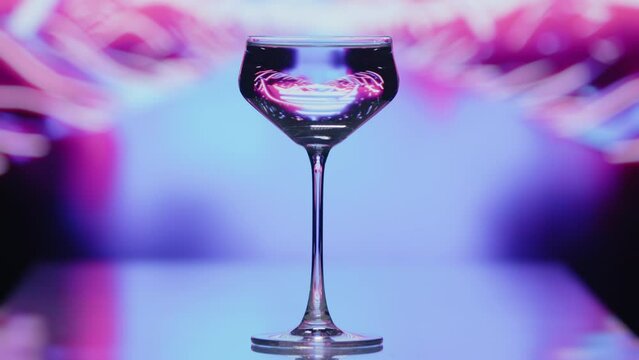 The clear wine glass stands infront of a road like blue and pink patterns. The patterns are moving at high speeds at the background. High quality 4k footage