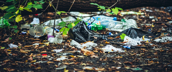 Garbage pile in forest among plants. Toxic plastic into nature everywhere. Rubbish heap in park...