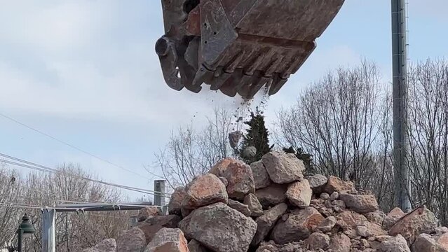Close up of a backhoe moving rocks to a pile