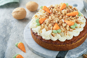 Easter Carrot cake with cream cheese frosting. Delicious carrot cake with walnut and cream cheese frosting on gray concrete background table for festive dinner. Traditional carrot cake. Easter food.