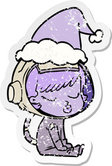 distressed sticker cartoon of a pretty astronaut girl sitting waiting wearing santa hat