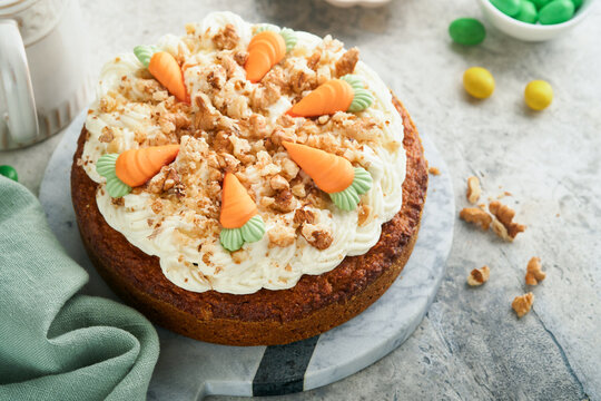 Easter Carrot cake with cream cheese frosting. Delicious carrot cake with walnut and cream cheese frosting on gray concrete background table for festive dinner. Traditional carrot cake. Easter food.