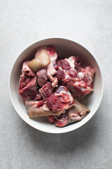 Fresh raw goat meat in a white bowl, chopped goat meat being prepared for cooking