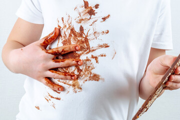 Chocolate stain on clothes. A child wiping out dirty chocolate hand on his clothes. isolated.