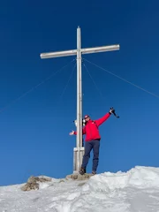 Fotobehang Hiker on top of peak with summit cross with snow landscape background © Wolfgang Hauke