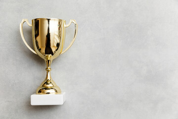 Simply flat lay design winner or champion gold trophy cup on concrete stone grey background. Victory first place of competition. Winning or success concept. Top view copy space - obrazy, fototapety, plakaty
