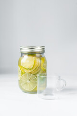 Glass cup and Lime in sugar syrup in a mason jar, Lime syrup for making tea, Lime slices in a sugar syrup